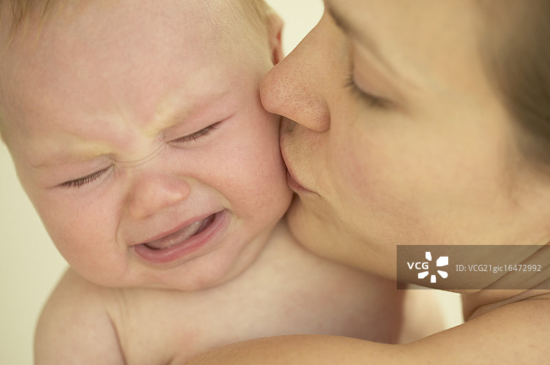 母亲亲吻哭泣的新生儿图片素材