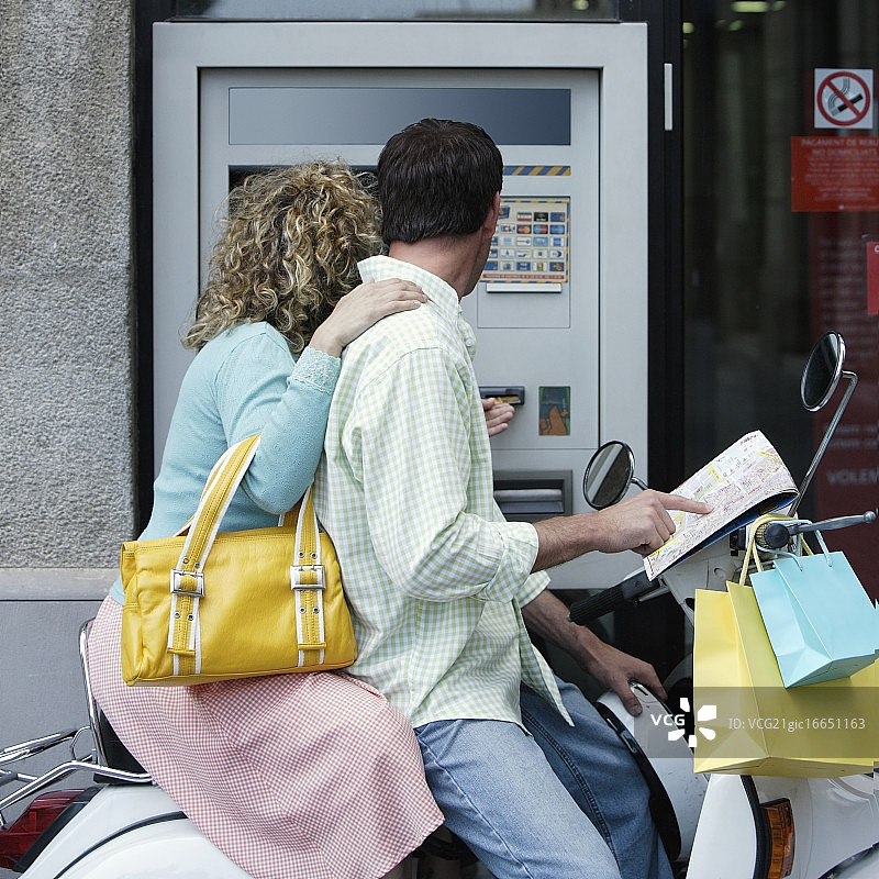 夫妇骑摩托车使用ATM机图片素材