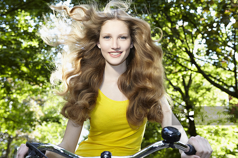 骑着自行车，头发被风吹乱的女人图片素材