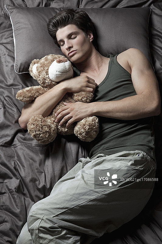 一个男人和泰迪熊睡觉图片素材