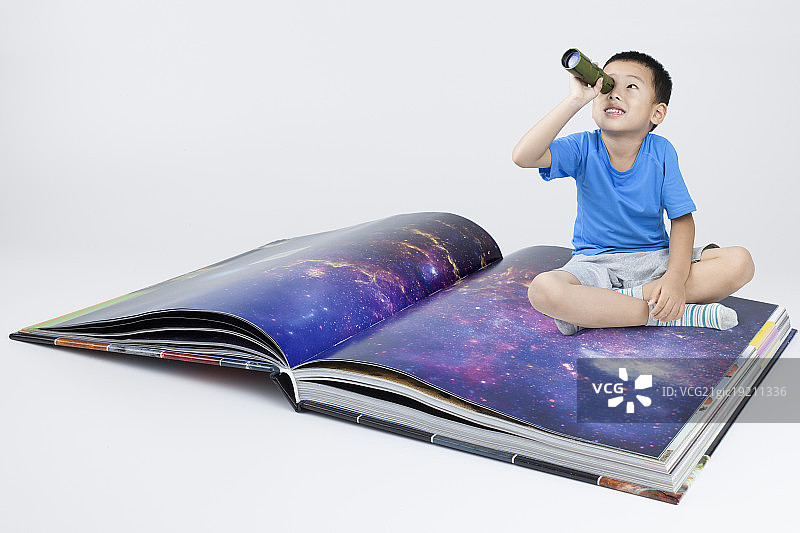 快乐的小男孩透过望远镜看天空图片素材