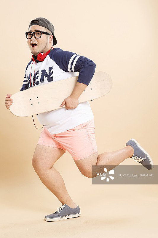欢乐的肥胖男人拿着滑板图片素材