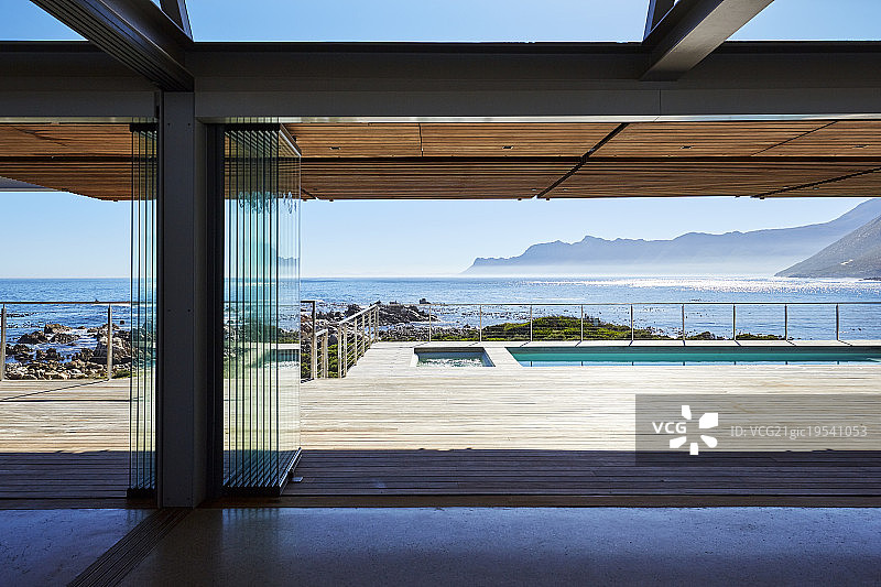 现代豪华住宅展示露台俯瞰游泳池和阳光明媚的海景图片素材