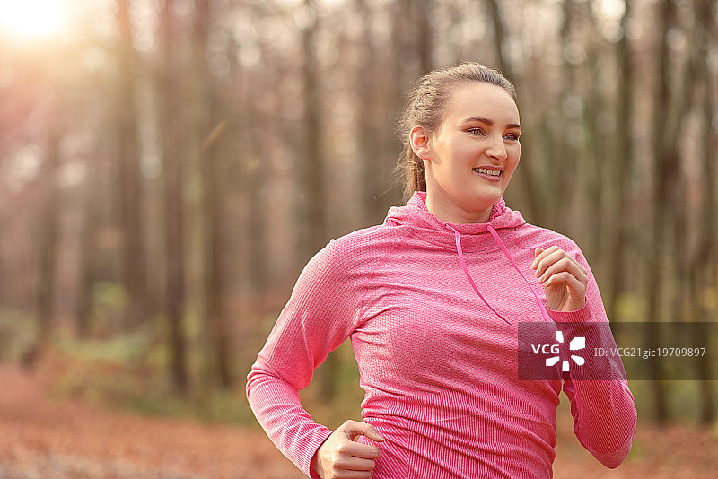 一个在树林里慢跑的健康年轻女人图片素材