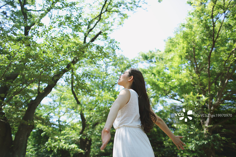 年轻的日本女人在城市公园被绿色包围图片素材