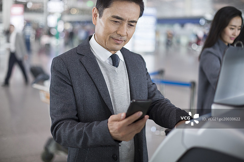 商务男士在机场使用自动售票机图片素材