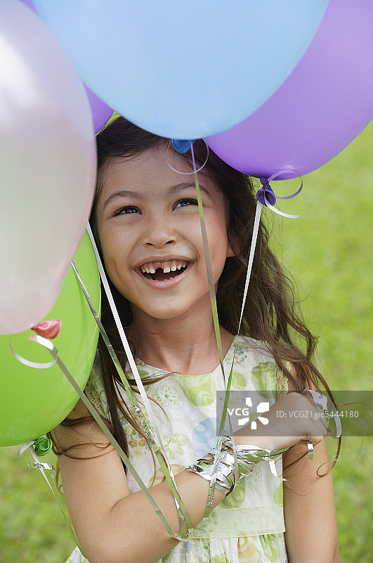 年轻的女孩拿着几个气球，微笑着图片素材