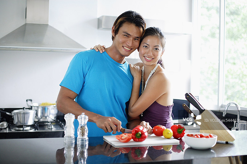 一对情侣站在厨房里，看着镜头，女人拥抱着男人图片素材