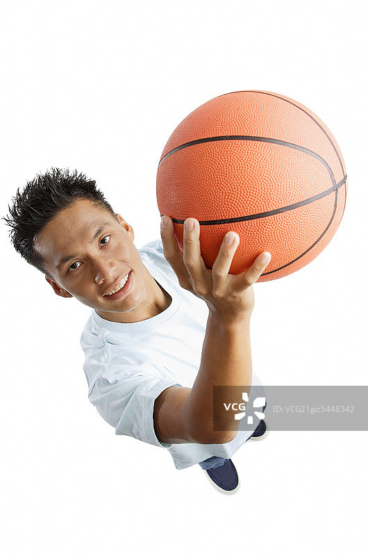 一个年轻人拿着篮球，抬头看着镜头图片素材