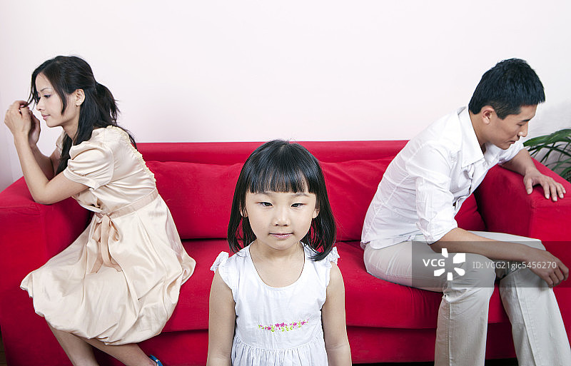 女孩们站着，吵架的父母坐在沙发上图片素材