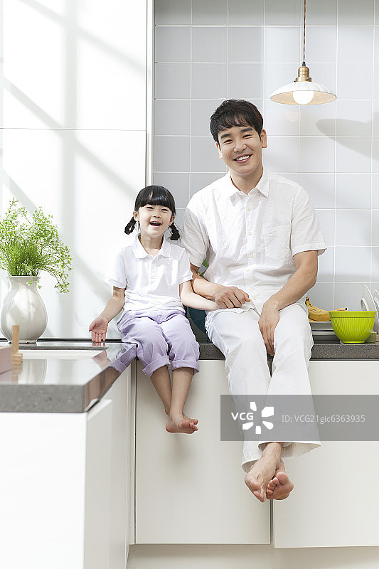 父亲和女儿坐在厨房柜台上图片素材