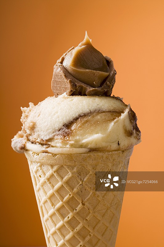 焦糖冰淇淋威化蛋筒在橙色背景图片素材