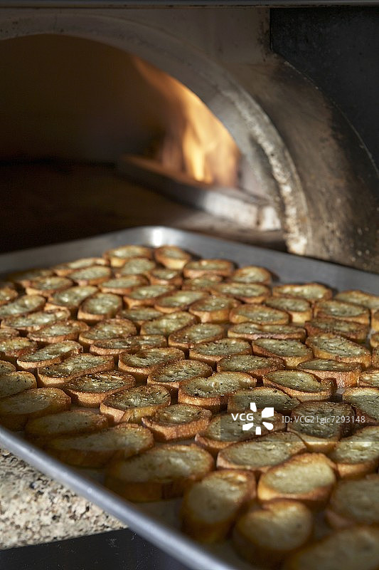 从披萨烤箱出来的法棍面包片放在平底锅上烤图片素材
