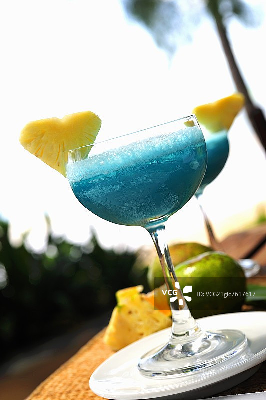 Blue Cura莽ao drinks with pineapple hearts on table outdoors图片素材