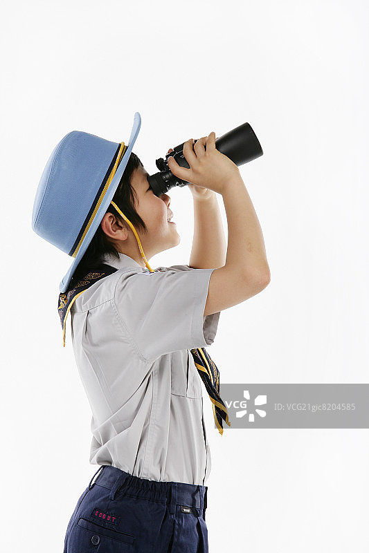 男孩(12-13岁)穿着童子军服装，通过双筒望远镜看侧面图片素材