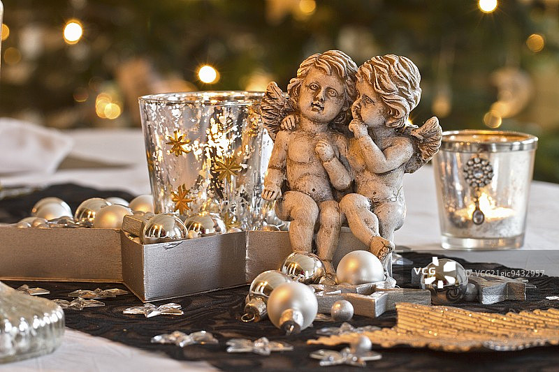 一对天使和圣诞装饰旁边的玻璃茶灯座图片素材