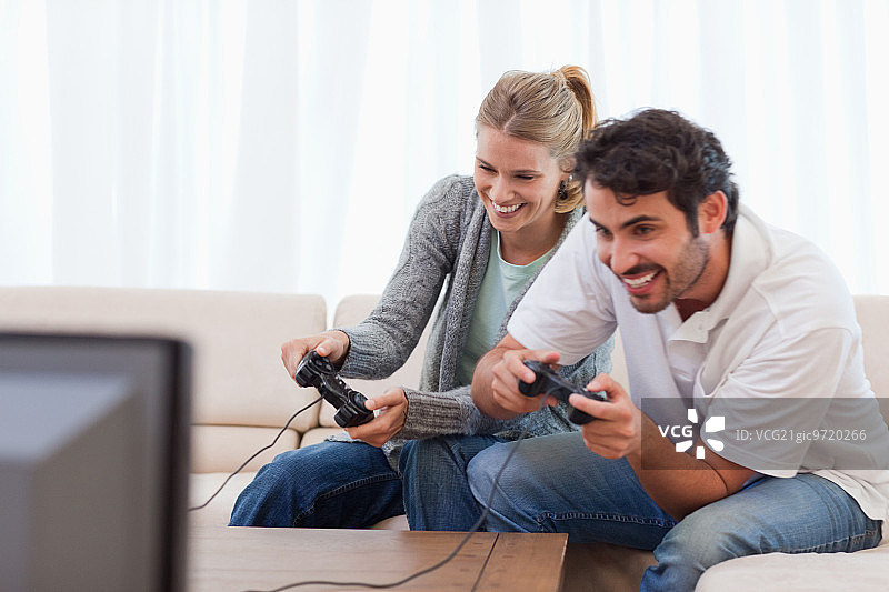 一对快乐的夫妇在他们的客厅里玩电子游戏图片素材