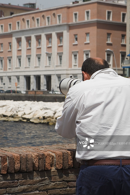 一个男人的后视图与一个手持望远镜，Via Partenope，那不勒斯湾，那不勒斯，那不勒斯省，坎帕尼亚，意大利图片素材