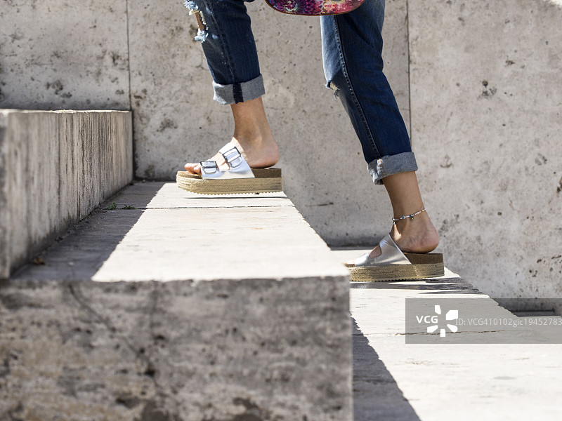 一个穿着夏天鞋子的年轻女人的脚和腿在户外爬楼梯图片素材