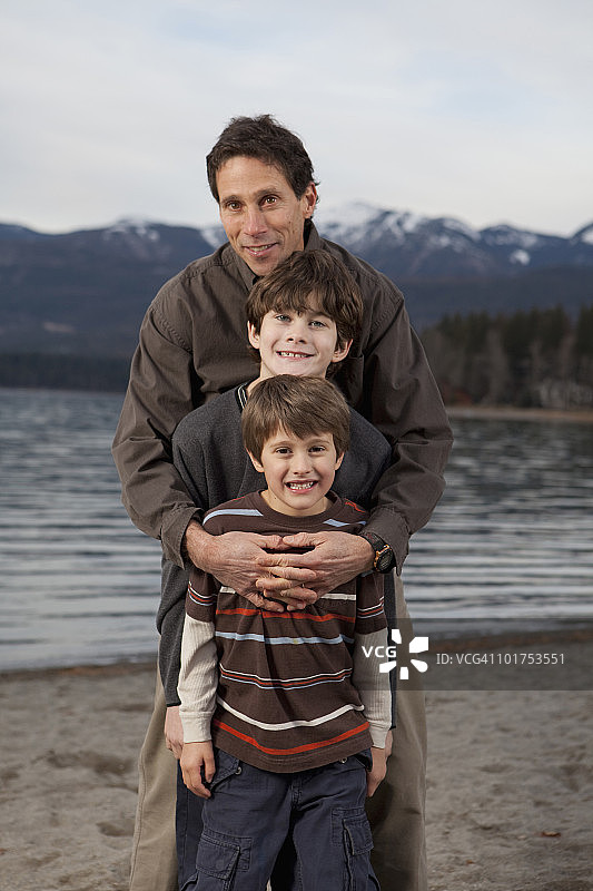 一个家庭在一个高山湖的海滩上拍照。图片素材