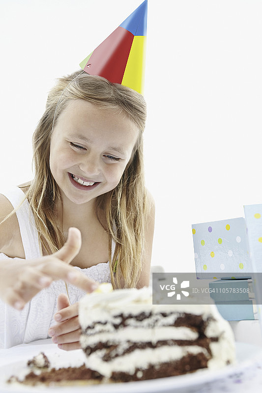 小女孩把手指放在生日蛋糕上的糖霜里图片素材