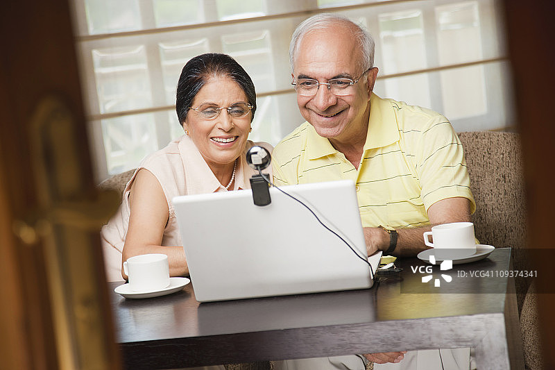 一对老年夫妇使用带有视频会议摄像头的笔记本电脑图片素材