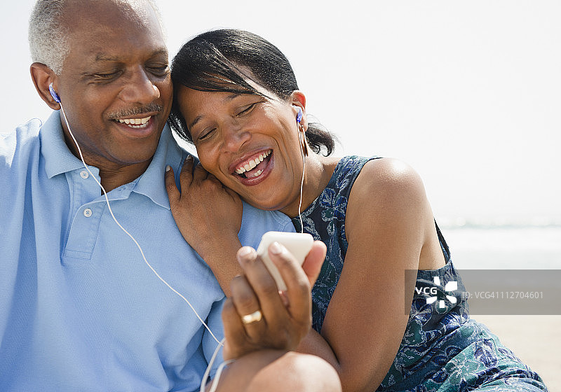 一对黑人情侣在海滩上一起听音乐图片素材