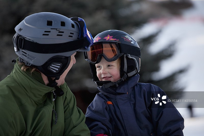 一对戴着头盔和滑雪面罩的父子在滑雪场图片素材