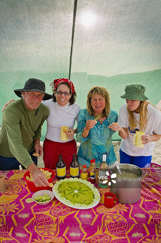 露营者享受新鲜的鳄梨色拉酱和啤酒图片素材