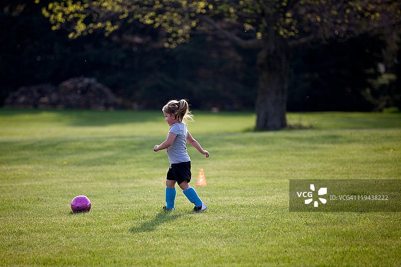 公园里的女孩正步行去踢足球图片素材