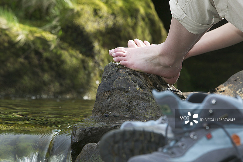 用步行靴把疲惫的双脚泡在山间小河里。图片素材