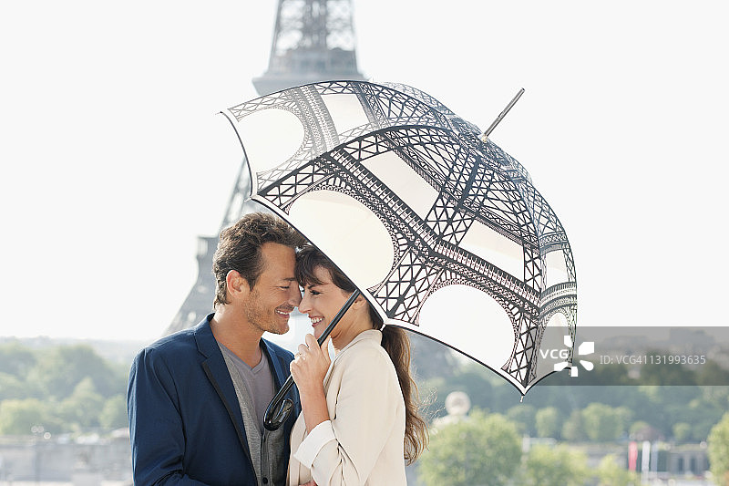 法国巴黎，一对夫妇在以埃菲尔铁塔为背景的雨伞下图片素材
