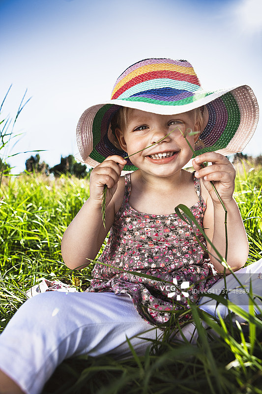 在草地上戴太阳帽的蹒跚学步的女孩图片素材