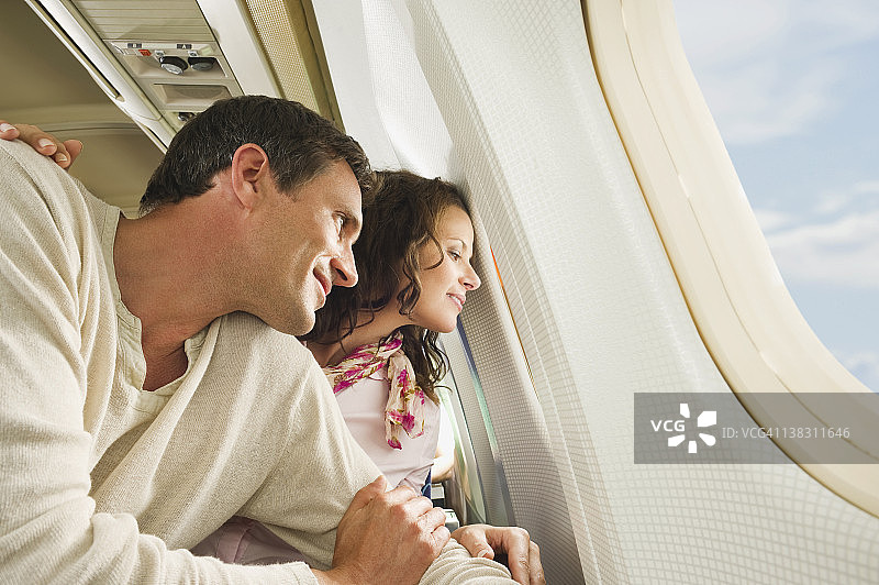 德国，慕尼黑，巴伐利亚，中年夫妇在经济舱的飞机上透过窗户往外看图片素材
