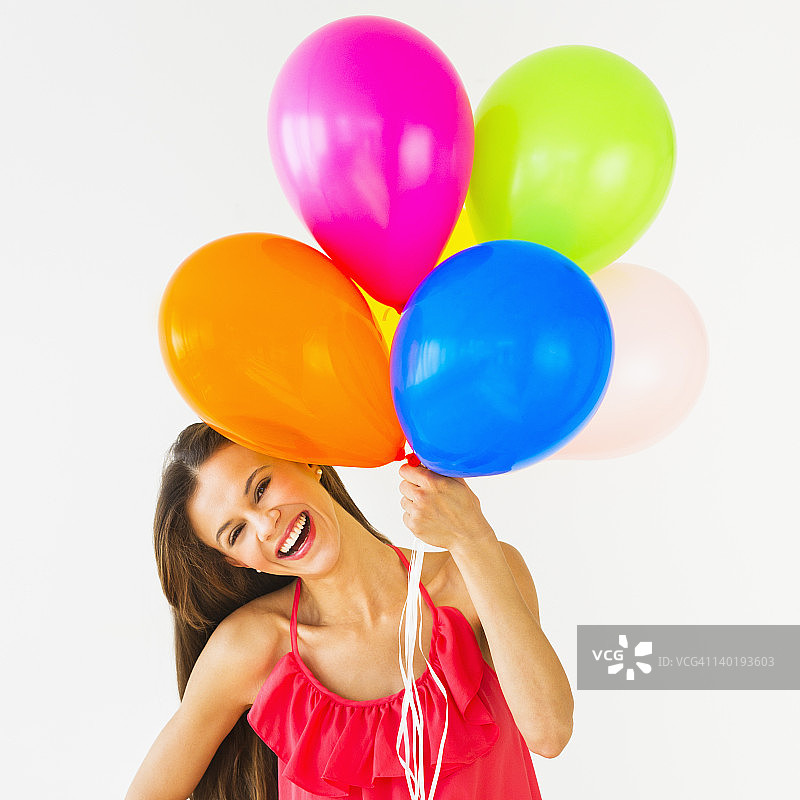 微笑的女人拿着气球，在摄影棚拍摄图片素材