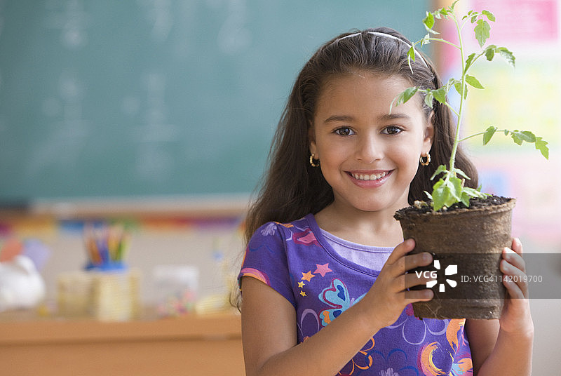 西班牙女孩在教室里抱着植物图片素材
