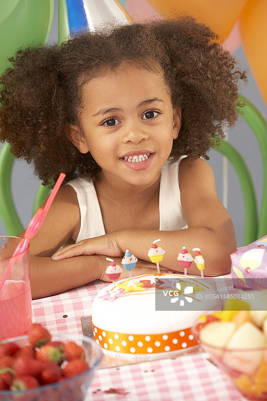 年轻的女孩和生日蛋糕在聚会上图片素材
