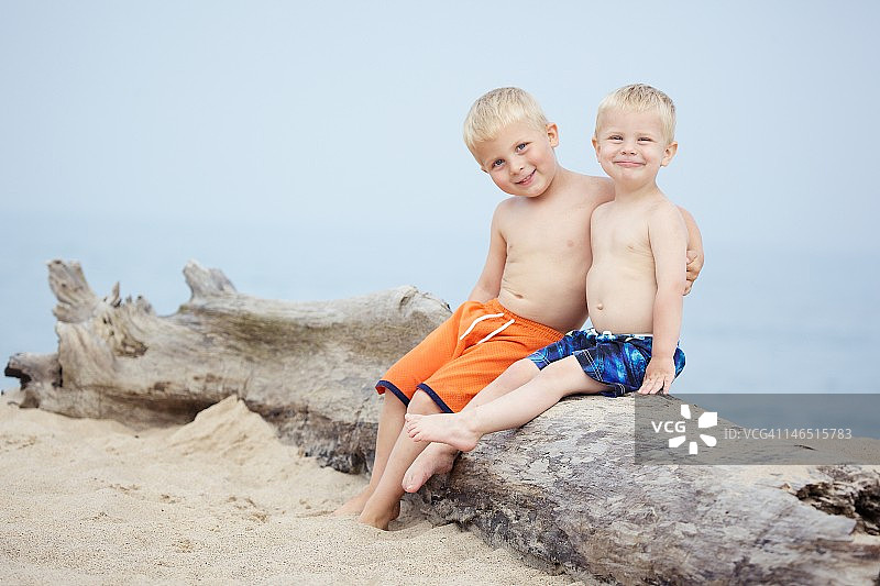 沙滩上男孩的肖像坐在圆木上图片素材