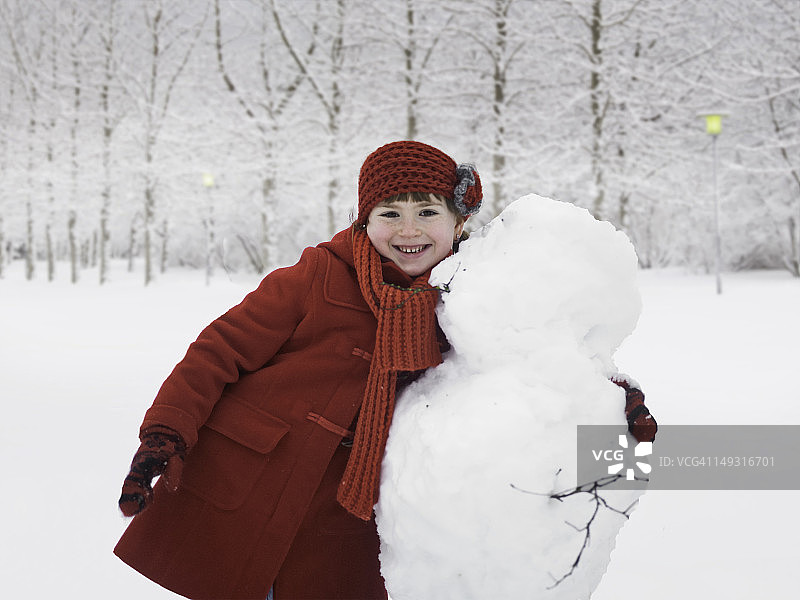 微笑的女孩在户外拥抱雪人图片素材