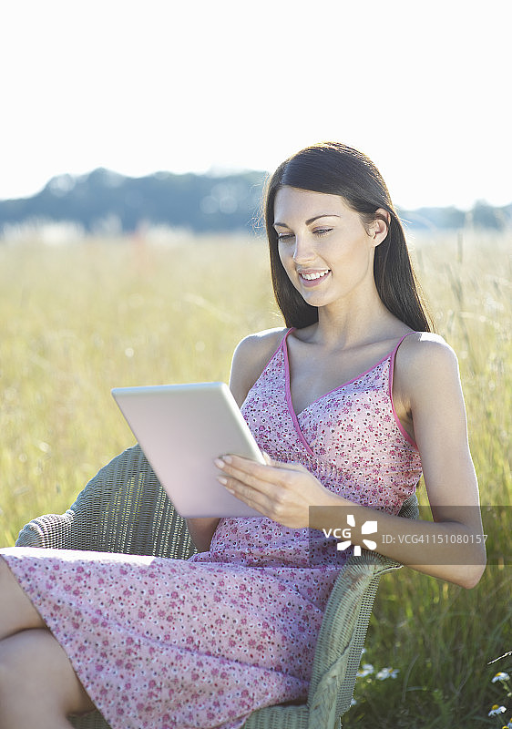 坐在农村使用平板电脑的妇女。图片素材