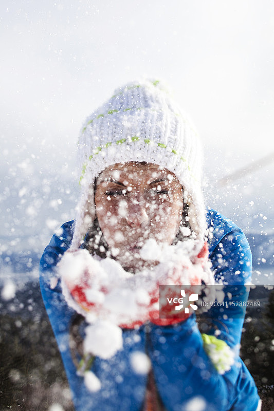 一位美丽的年轻女子在爱达荷州的冬季徒步旅行中吹雪。图片素材