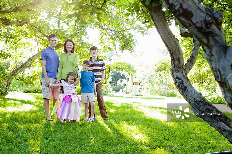 快乐家庭与树孩子(4- 5,6 - 7,12 -13)在花园里图片素材