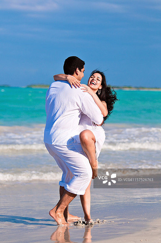 一对快乐的情侣在沙滩上跳舞图片素材