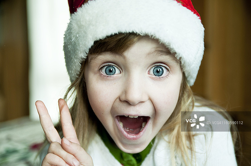 戴着圣诞老人帽的兴奋小女孩图片素材