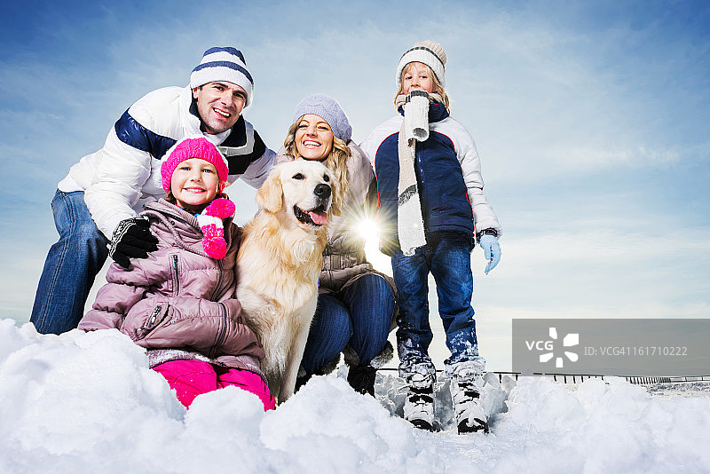 一家人和他们的狗在雪中享受。图片素材