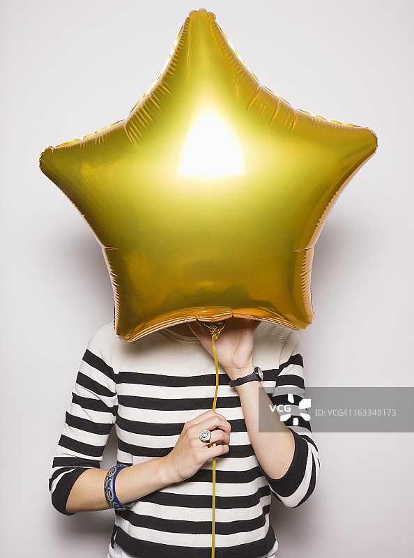 脸被气球遮住的年轻女子图片素材