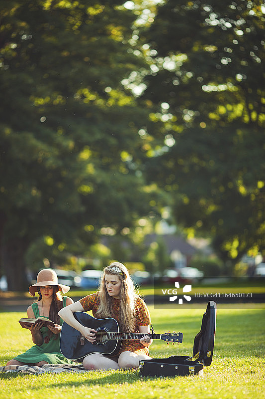 两个快乐的夏日公园朋友在户外弹吉他图片素材