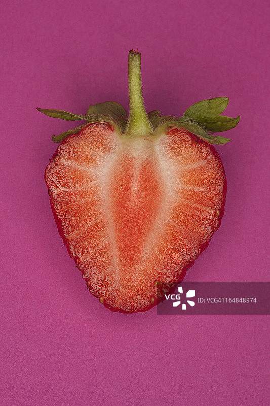粉色背景上切成一半的草莓图片素材