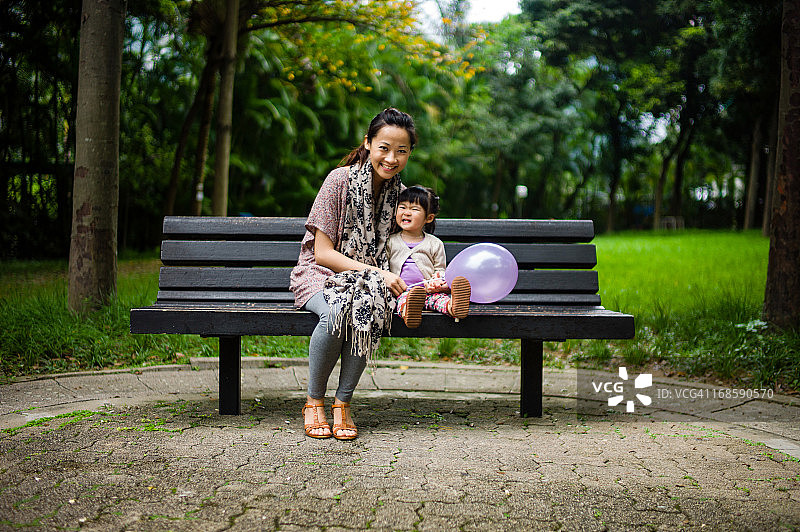 漂亮的妈妈和孩子坐在长凳上微笑图片素材