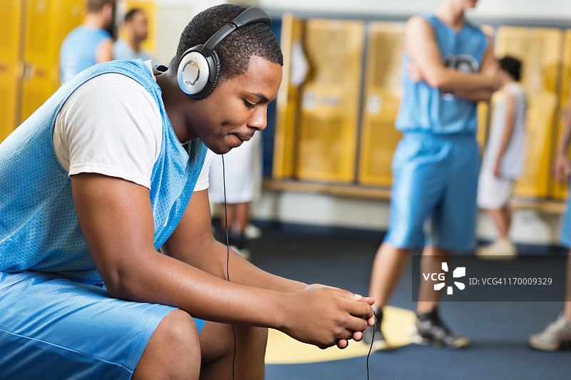 严肃的篮球运动员在更衣室里听音乐图片素材